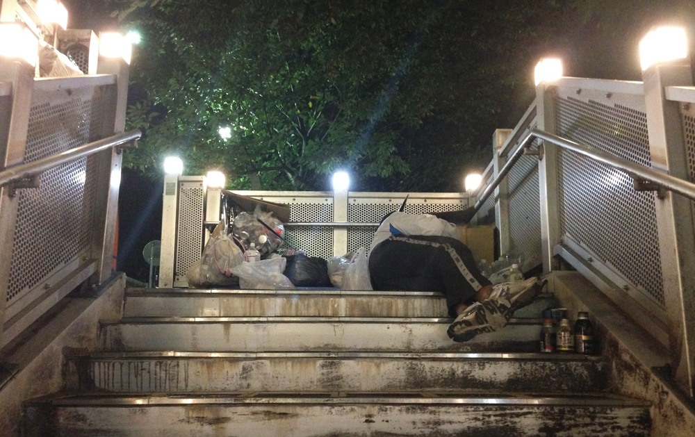 A homeless man sleeps on a bridge near Nogizaka Station
