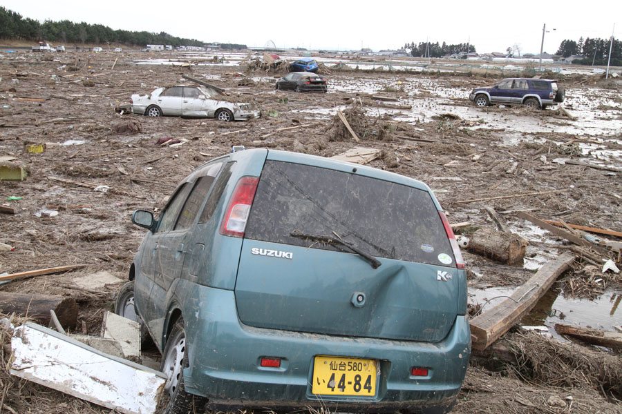 Cars moved by the tsunami sit in a field in Wakabayashi Ward