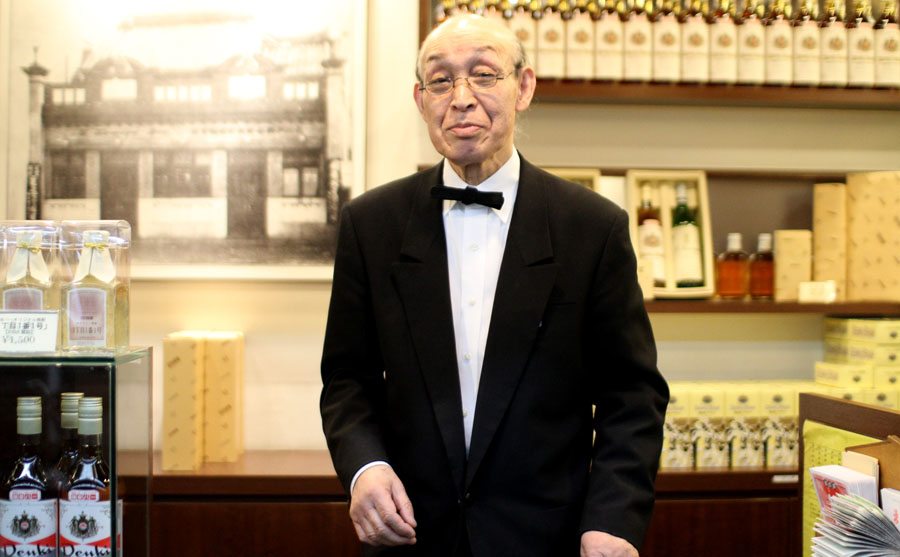 Shopkeeper at Kamiya Bar in Tokyo's Asakusa district displays bottles of Denki Bran, the bar's signature brandy-like drink