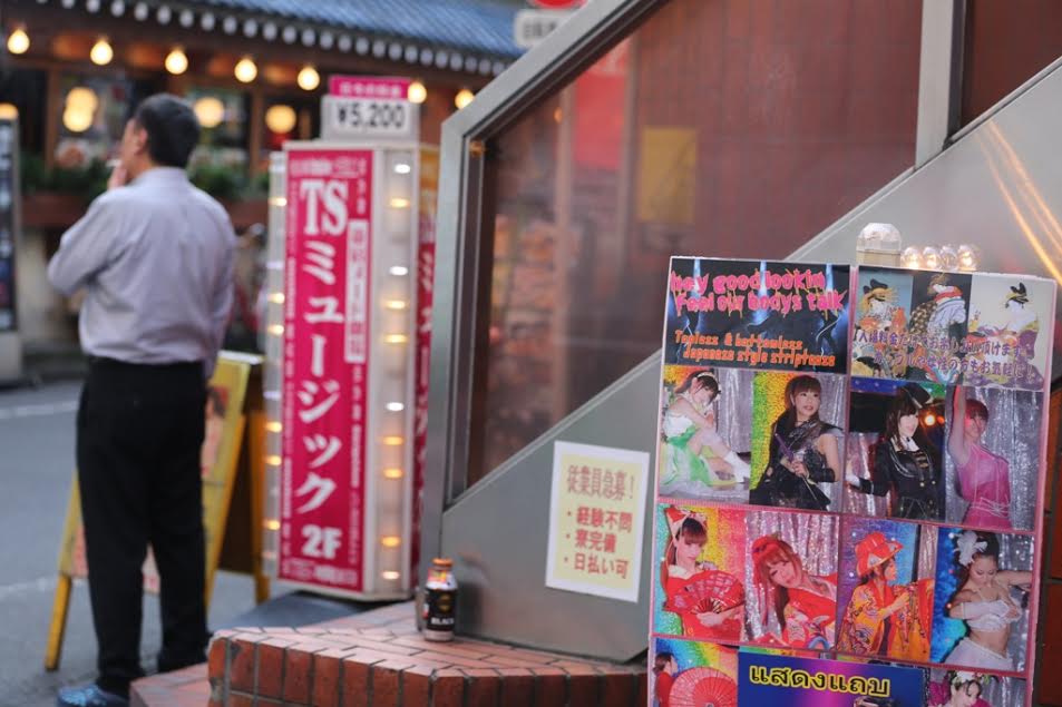 A man smokes a cigarette in front of strip club T.S. Music in Kabukicho (The Tokyo Reporter)