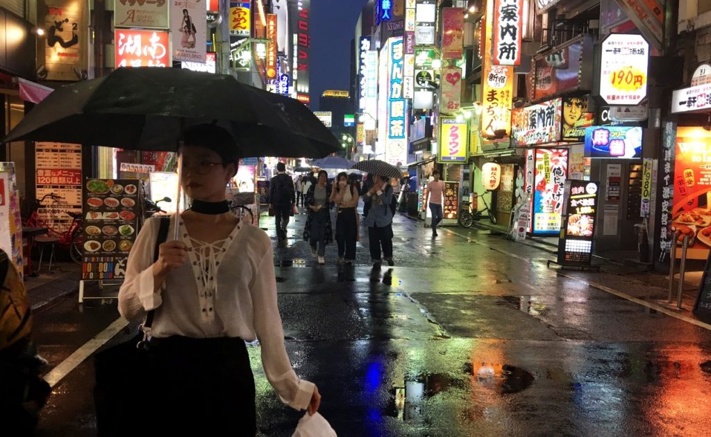 A woman holds an umbrella in the Kabukicho red-light district in June