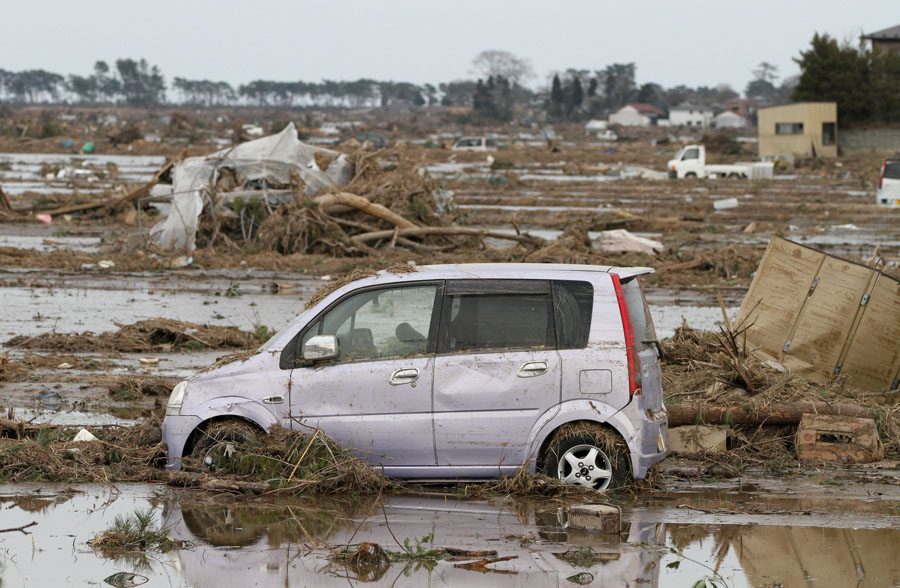 A car moved by the tsunami sits in a field in Wakabayashi Ward